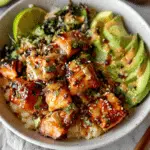 Honey glazed salmon bowl with avocado, rice, and creamy sauce drizzle