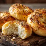 Freshly baked, golden Onion Yogurt Bagels with a glossy crust and savory toppings, sliced open to show the soft interior.
