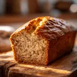 Moist sourdough discard banana bread sliced on a wooden board showing soft tender crumb and golden crust