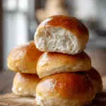 Golden sourdough hamburger buns with soft fluffy interior on a wooden board