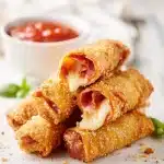 Golden-brown crispy pizza egg rolls filled with melted mozzarella and pepperoni, with marinara dipping sauce, natural light.