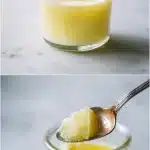 A tall clear glass of golden gelatin drink with honey and vanilla, topped with a lemon slice, on a wooden table with natural light.