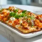 Freshly baked kimchi pizza on dark slate with scallions and sesame seeds