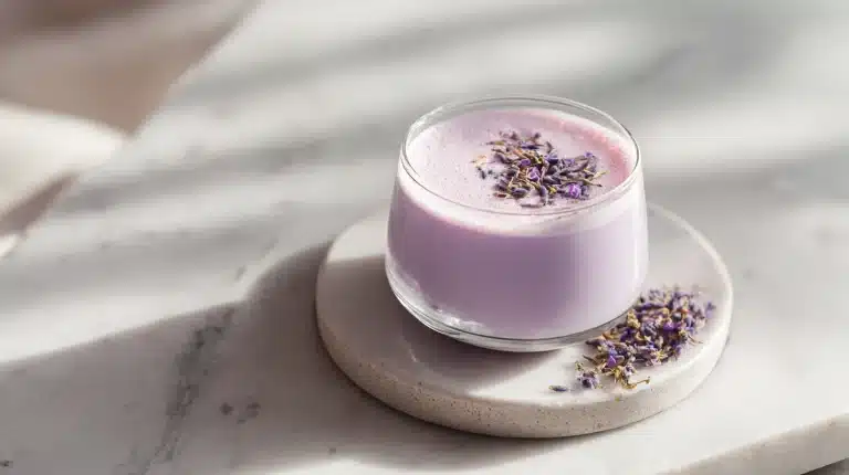 Steaming mug of lavender moon milk topped with rose petals on marble