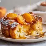 Peach french toast recipe baked golden in a white ceramic dish with caramelized peaches