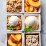 Close-up overhead view of a bubbling golden peach cobbler baked in a black cast-iron skillet, topped with scoops of melting vanilla ice cream. Fresh, sliced ripe peaches and scattered cinnamon sticks surround the skillet on a rustic wooden table, evoking a warm summer dessert scene with these peach recipes.