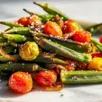 Golden charred sautéed okra recipe in a cast iron skillet with onions and tomatoes