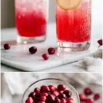 A tall glass of fizzy, pale pink acv baking soda tonic garnished with fresh lemon wheels and floating cranberries, sitting on a bright white marble countertop beside a bottle of raw apple cider vinegar.