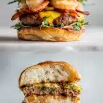 A stacked Cajun surf and turf burger with golden beef, pink shrimp, andouille, and fresh lettuce and tomato under soft light.