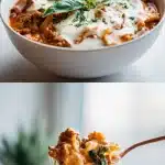 Close-up of a steaming bowl of creamy lasagna soup featuring broken lasagna noodles, a rich and hearty meat sauce, and a generous swirl of melted mozzarella and cream, garnished with fresh green basil leaves on a rustic table.
