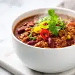 A warm bowl of easy meatless chili recipe topped with cheese and cilantro.