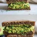 Close-up of a thick, creamy high protein smashed chickpeas sandwich on dark sprouted grain bread, layered with mashed avocado, red onion, and fresh dill, with a side of crunchy vegetables on a wooden board.
