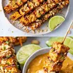 Close-up of golden-brown grilled high protein tofu satay skewers on a rustic plate, generously drizzled with glossy peanut sauce, garnished with crushed peanuts, fresh cilantro, and lime wedges on a dark wooden table.