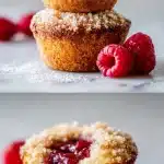 Jam filled donut muffin with cinnamon sugar crust and glossy raspberry jam center on light marble with fresh raspberries and powdered sugar.