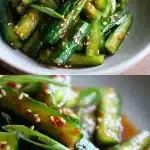 Vibrant Korean cucumber salad in a ceramic bowl, coated in a glossy red gochugaru dressing with visible green onion slices and scattered sesame seeds, set on a light wooden table.