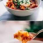 An overhead view of a rustic white bowl filled with a chunky, red Vegetarian Lasagna Soup. Visible are wide, broken lasagna noodles, diced carrots, and spinach, topped with a melting dollop of white ricotta cheese, a sprinkle of shredded mozzarella, and vibrant green basil leaves. A spoon rests beside the bowl on a wooden table.
